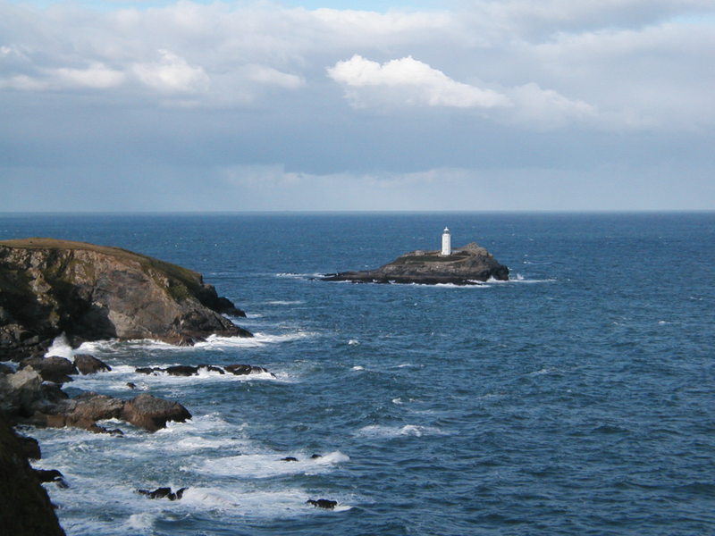Lighthouse on a small island just off a low headland.