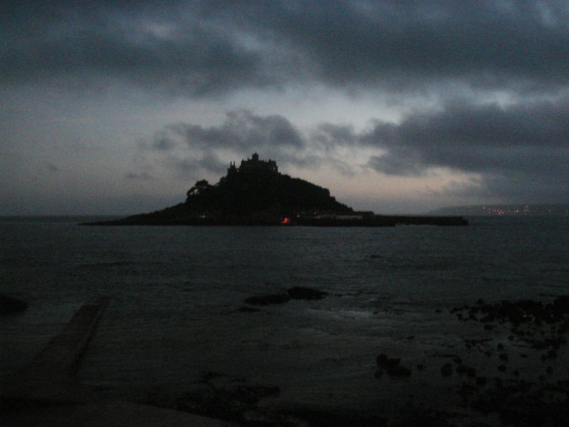 Small island with castle at the top of it, sillhouetted in evening light