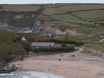 Looking across a beach to a small church, the tower seems to be half buried in the hillside