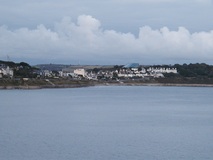Looking across sea to lots of white houses and buildings, bank of cloud in background