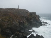 Rugged cliffs with rough sea below and old ruined mine building and chimneys above