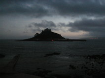 Small island with castle at the top of it, sillhouetted in evening light