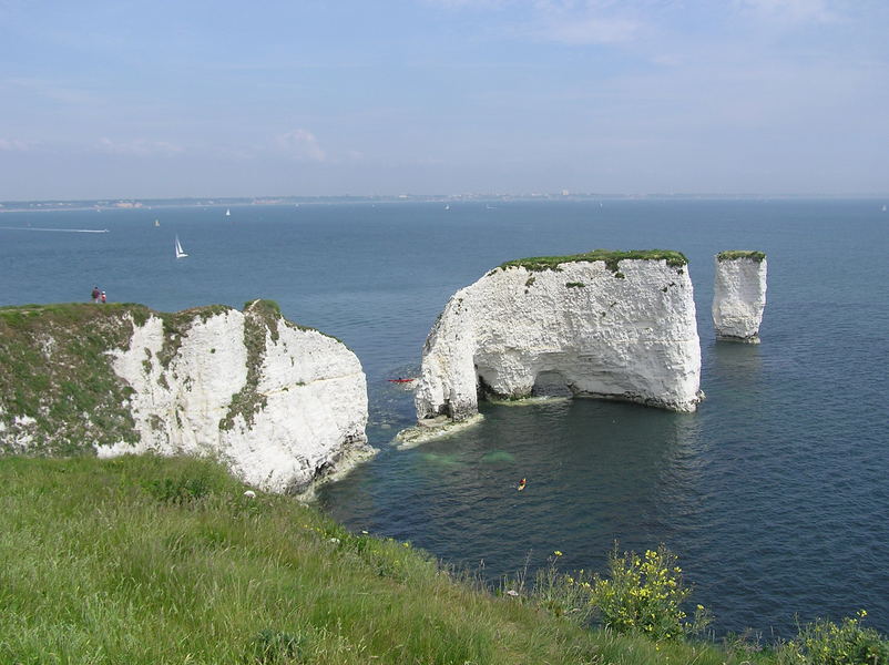 Chalk sea stacks, with grassy tops, sunshine and blue skies.