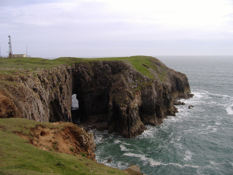 Rocky headland with grass covered top and arch